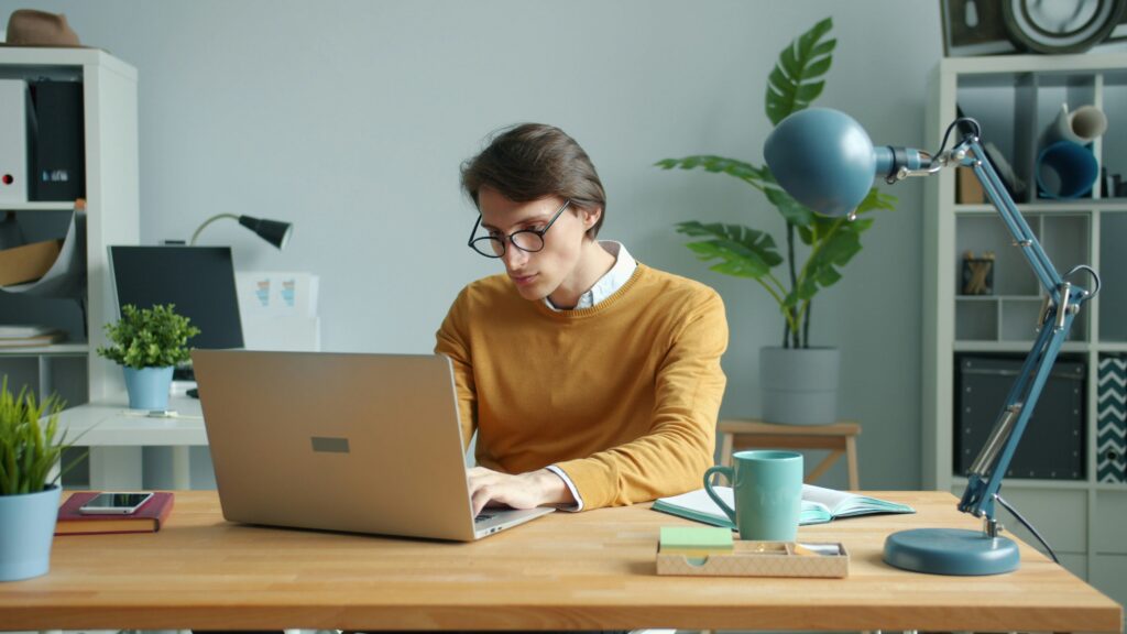 A person working on a laptop at a home desk, earning money online.