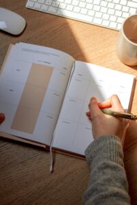 A person planning their day with a calendar and notebook to improve time management skills.